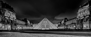 Pyramide du Louvre et façade historique illustrant l'équilibre entre innovation architecturale et patrimoine français, métaphore de la transformation organisationnelle maîtrisée